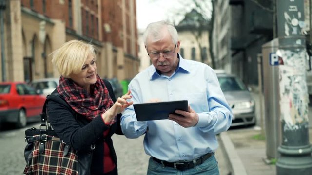 Mature couple lost in city and checking map on tablet computer
