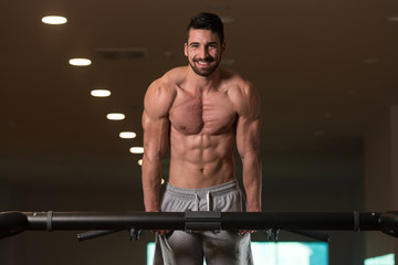 Fototapeta na wymiar Young Bodybuilder Exercising Triceps Doing Dips on Bar