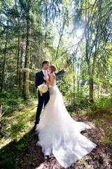 Wedding couple on the nature is hugging each other. Beautiful model girl in white dress. Man in suit. Beauty bride with groom. Female and male portrait. Woman with lace veil. Lady and guy outdoors