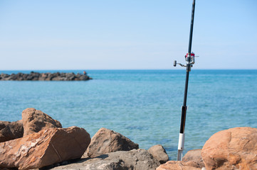 Fishing pole with red reel on blue sea