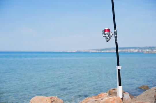 Fishing pole with red reel on blue sea