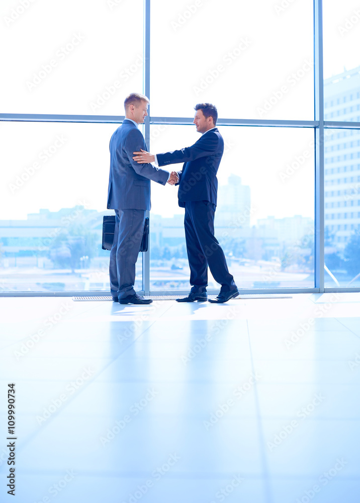 Wall mural full length image of two successful business men shaking hands with each other