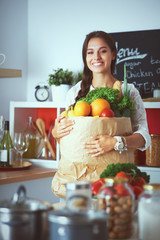 Young woman holding grocery shopping bag with vegetables 