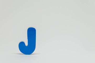 Blue wooden alphabet J with white background and selective focus