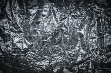 Background of scratched and crumpled black paper with selective focus and under exposure