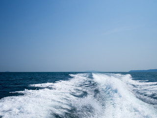 Restless foamy blue sea wake water on the sea water surface with clear blue sky while travel by speed boat in the ocean.