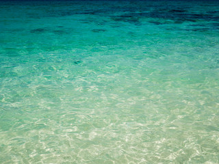 Background of transparent crystal blue sea water surface in summer.