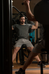 Obraz na płótnie Canvas Young Bodybuilder Exercising Shoulders On Machine