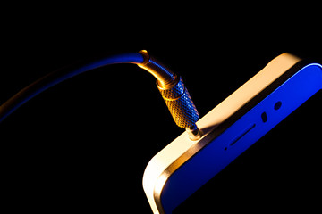 audio jack is connected to a mobile phone isolated on a black background executed in macro technique