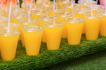 Orange juice in plastic cups with straws