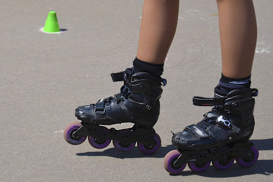 Leggs of roller skating young girl training with inline rollerblades.