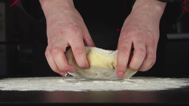 SLOW: A cook throws up a dough on a table in the kitchen