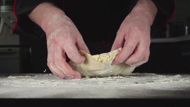 SLOW: A baker kneads a dough in a kitchen