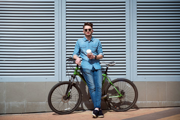 Pleasant guy standing with his bicycle 