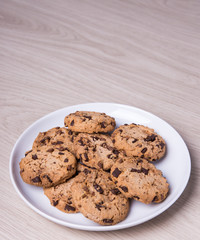 close up of chocolate chip cookies on white plate and copy space