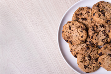 top view of chocolate chip cookies on white plate and copy space