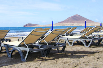 Two sunbeds on  a beautiful beach de Medano,Tenerife, Canary Islands. Concept for vacations or tourism