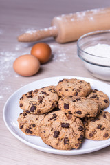 chocolate chip cookies, eggs and flour on wooden background