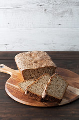 Homemade dark rye sourdough bread loaf and sliced on round chopping board. Vertical image with copy space.
