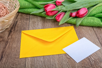 Envelope with sheet of paper and tulips on a wooden background