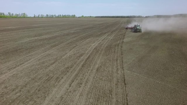 AERIAL: big tractor sowing spring wheat in the field
