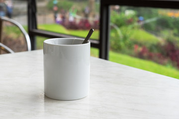White mug of hot tea with tea bag on table in tea shop