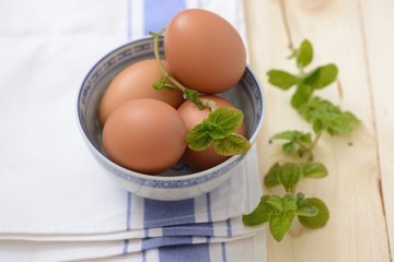 brown eggs in a bowl with mint leaf on a napkin closeup