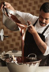 Black man professional chief pours tasty melted chocolate from o