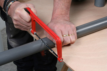 Plumber cutting pvc pipe with a saw