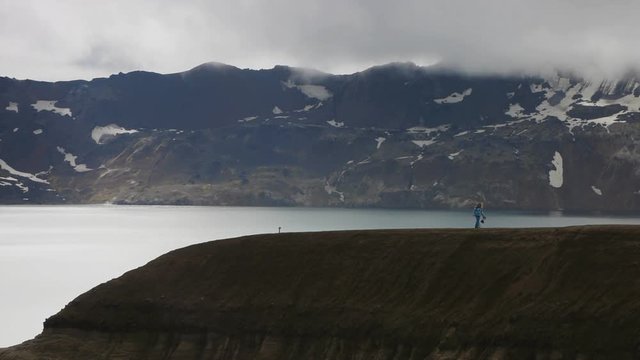 tourist woman walking on volcano crater rim edge askja iceland