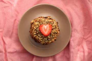 Simple cookies prepared with two ingredients: oatmeal and mashed bananas. Decorated with strawberry. Top view, selective focus. 