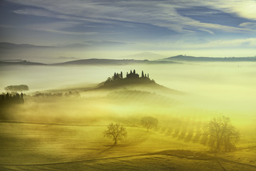 Tuscany foggy morning, farmland and cypress trees. Italy.