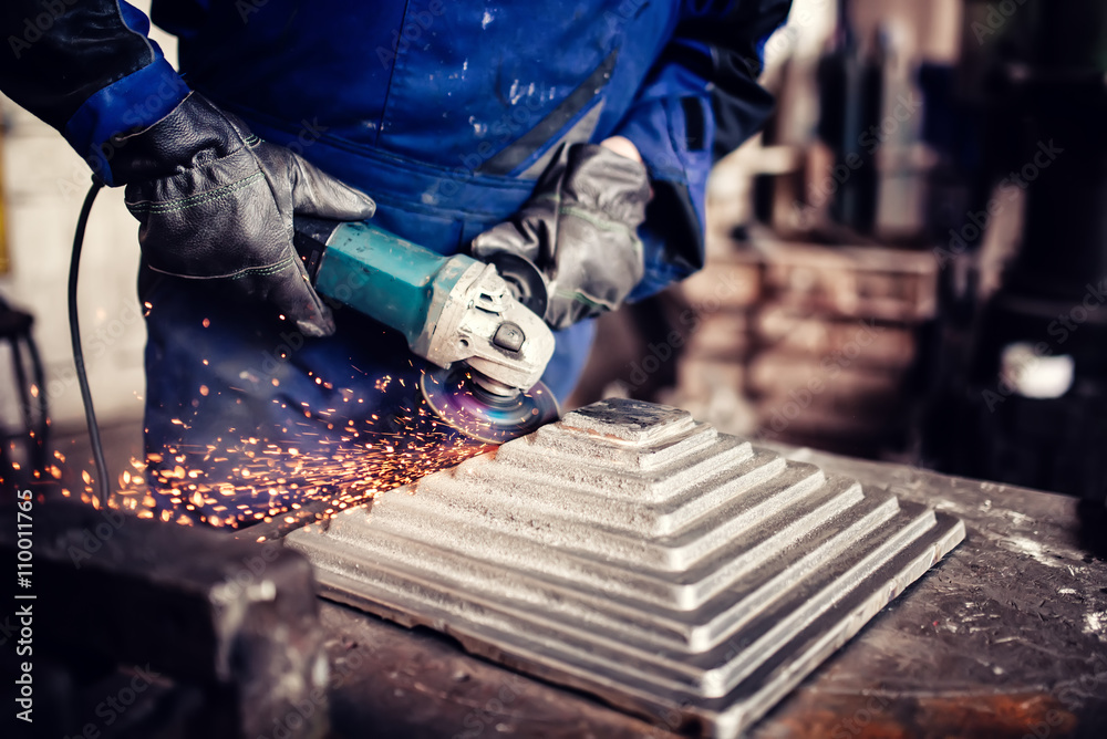 Wall mural industrial engineer working on cutting a metal and steel bar with angle grinder, metallurgic factory