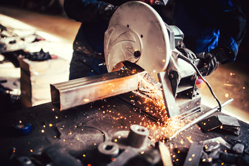 worker with grinding machine, power tool in factory. Details of cutting steel and iron