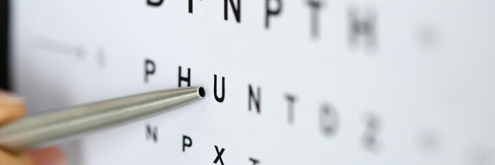 Silver ballpoint pen pointing to letter in eyesight check table - obrazy, fototapety, plakaty