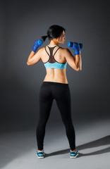 Woman stands from the back in fitness suit