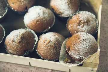 Simple muffins in a wooden box covered with powder sugar 