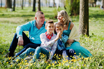 Naklejka na ściany i meble Happy pregnant family with two sons, dressed in a turquoise clot