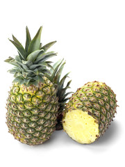 two pineapples on white showing one cut