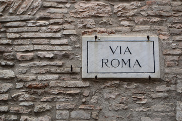 Straßenschild - Via Roma vor Natursteinwand