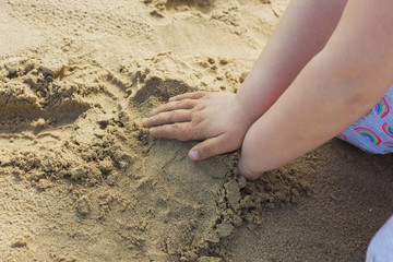 Girls hands playing in the sand at the beach.