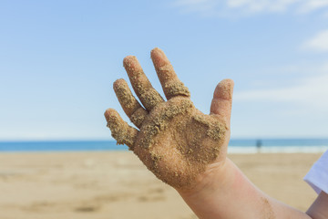 Close up hand with wet sand of a 5 year old kid