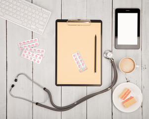 workplace of doctor - stethoscope, pills, clipboard, tablet pc