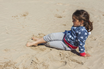 Girl posing in the sand of the beach in a windy day in Easter. S