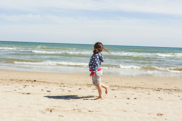 Fototapeta na wymiar Rear view full shot girl walking to the shore of the beach in a