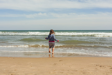 Rear view full shot girl walking to the shore of the beach in a
