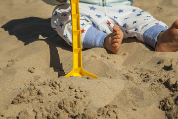 Close up baby boy playing with sand toys at the beach.