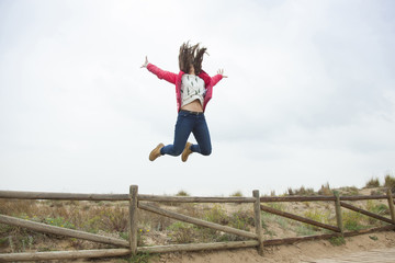 Full shot happy teenager jumping with outstretched hands near th