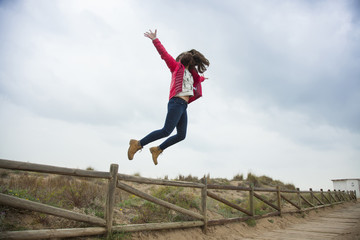 Full shot happy teenager jumping with outstretched hands near th