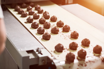Dark brown sweets with shavings. Dark candies on beige cloth. Sweet product of quality chocolate. Production of tasty dessert.